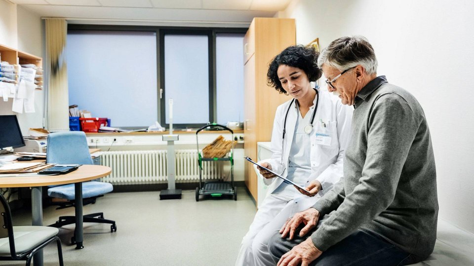 A medical professional explains a chart to their patient in an exam room